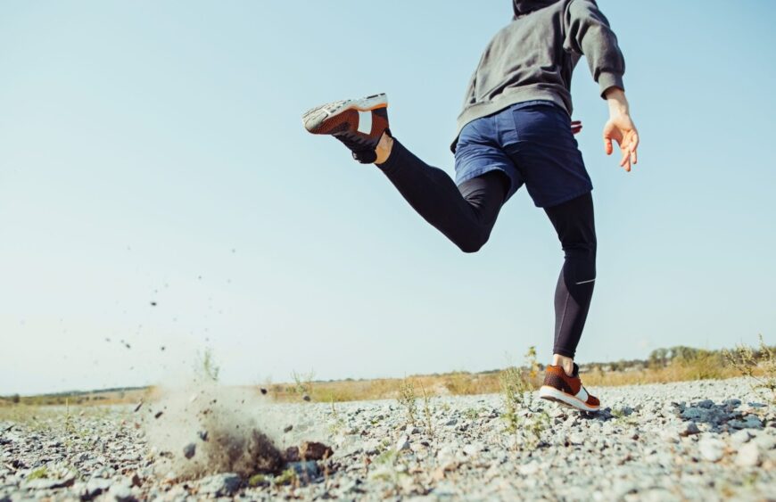 Running sport. Man runner sprinting outdoor in scenic nature. Fit muscular male athlete training trail running for marathon run.